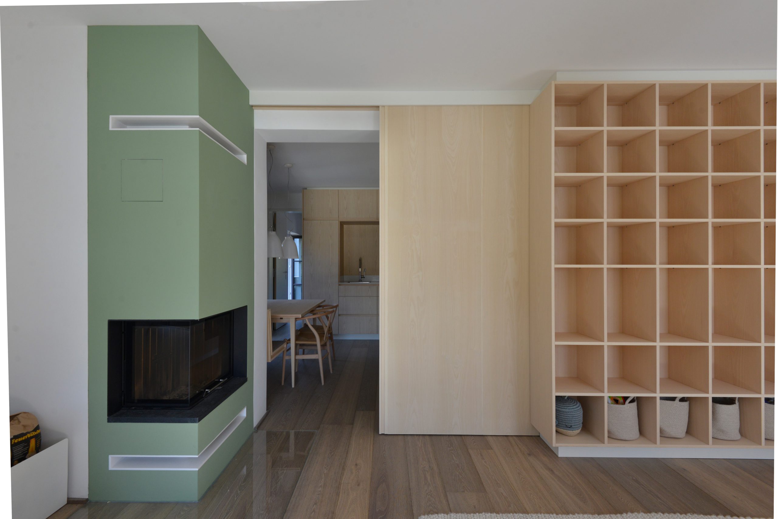 Für eine Wohnung in Mittenwald haben RKK Architekten ein modernes Stauraumkonzept entwickelt, das durch ein großes Regal und eine elegante Sitzbank überzeugt.